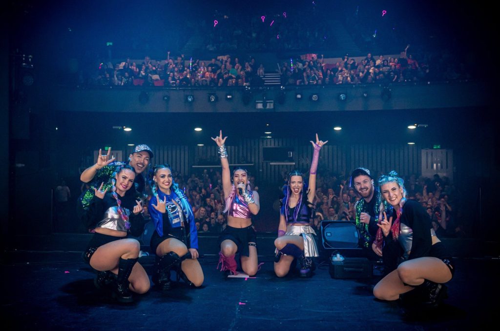 The K-Pop Fantasy cast take a bow in front of a packed theatre audience waving light sticks