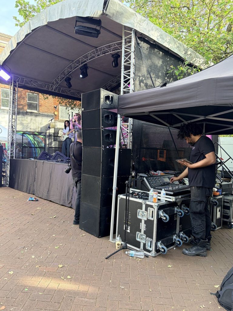 Valcato sound engineer at the mixing desk beside the stage and PA